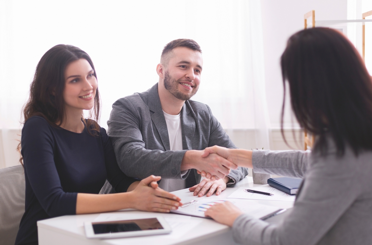 Young family handshaking with expert, ready to sign contract